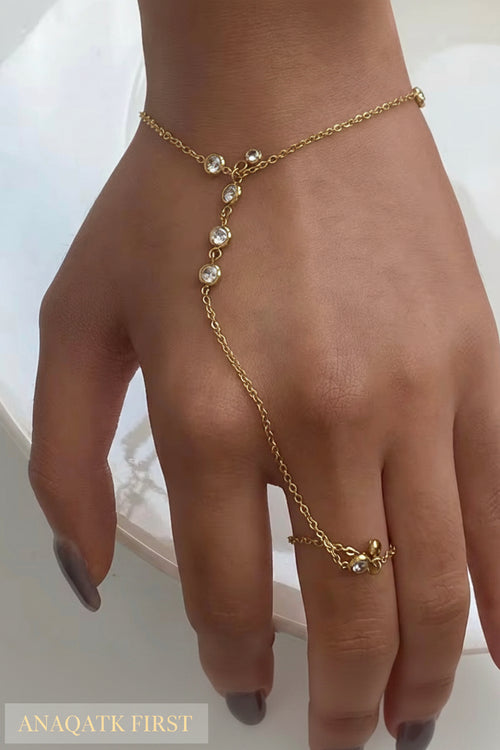Gold bracelet with pearl-like stones on a hand against a white background