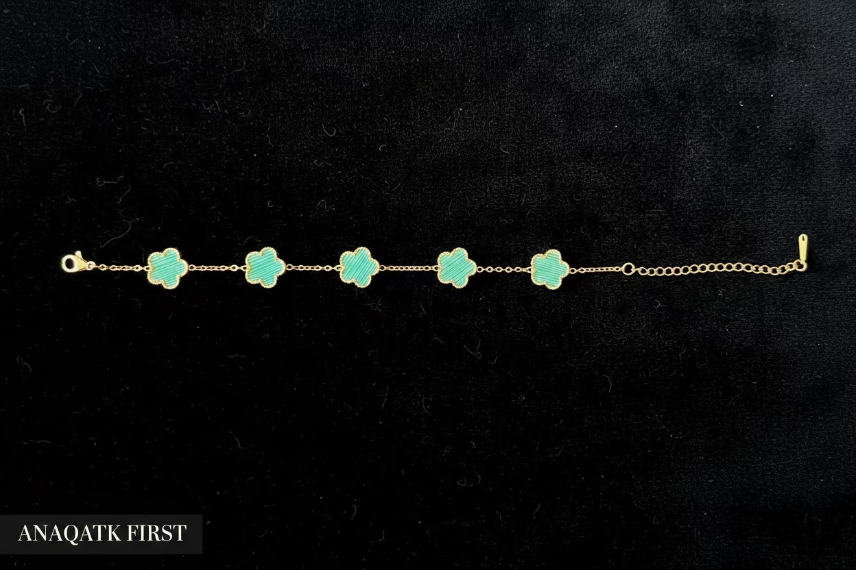 Gold bracelet with green clover-shaped charms on a black background