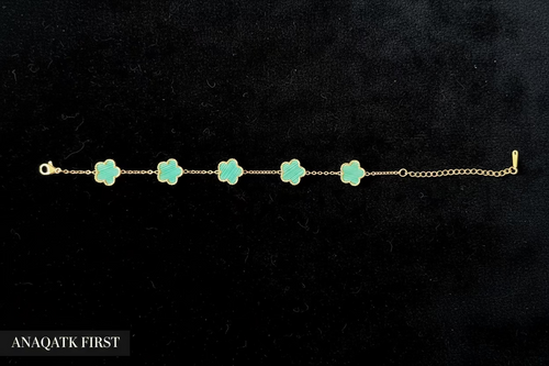 Gold bracelet with green clover-shaped charms on a black background