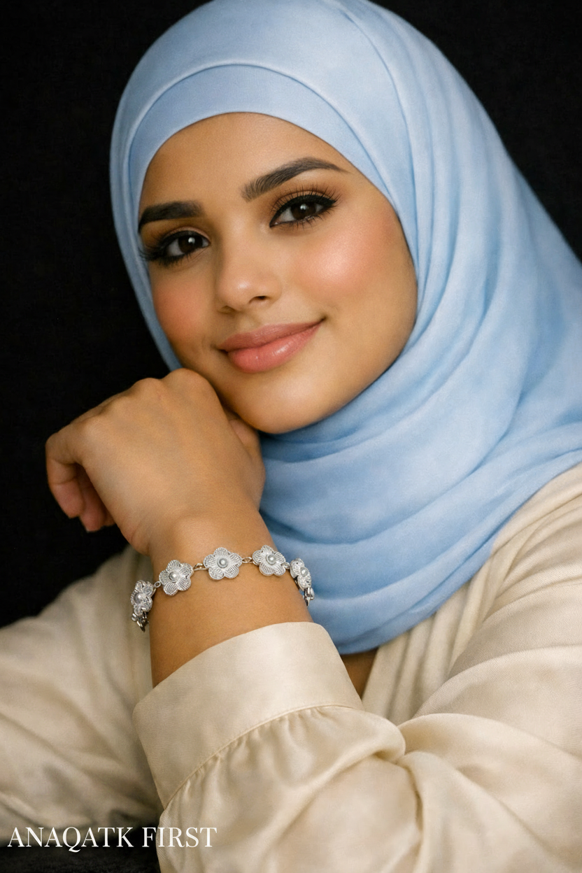Woman wearing a light blue hijab and a bracelet with a dark background