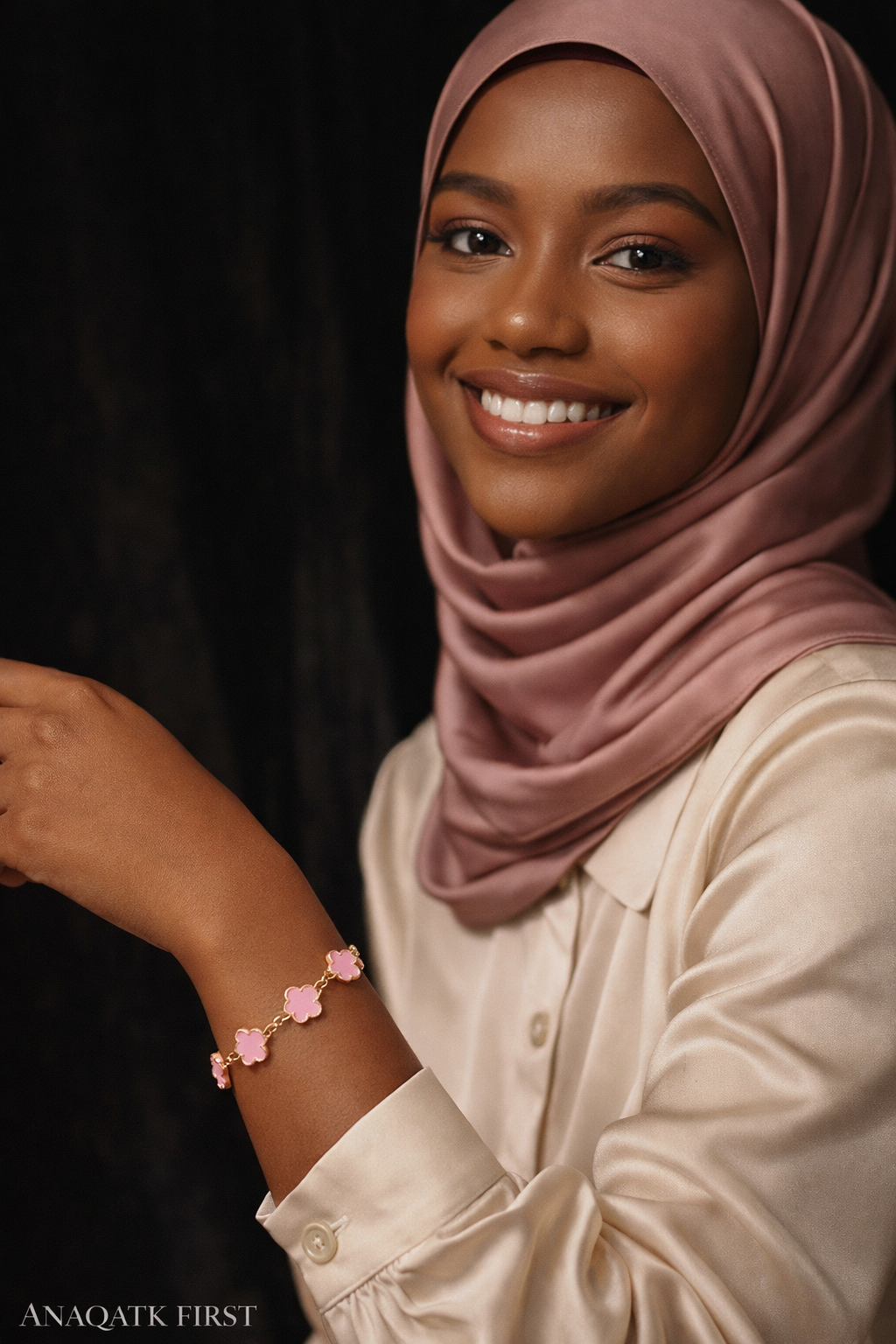Woman wearing a pink hijab and bracelet against a dark background