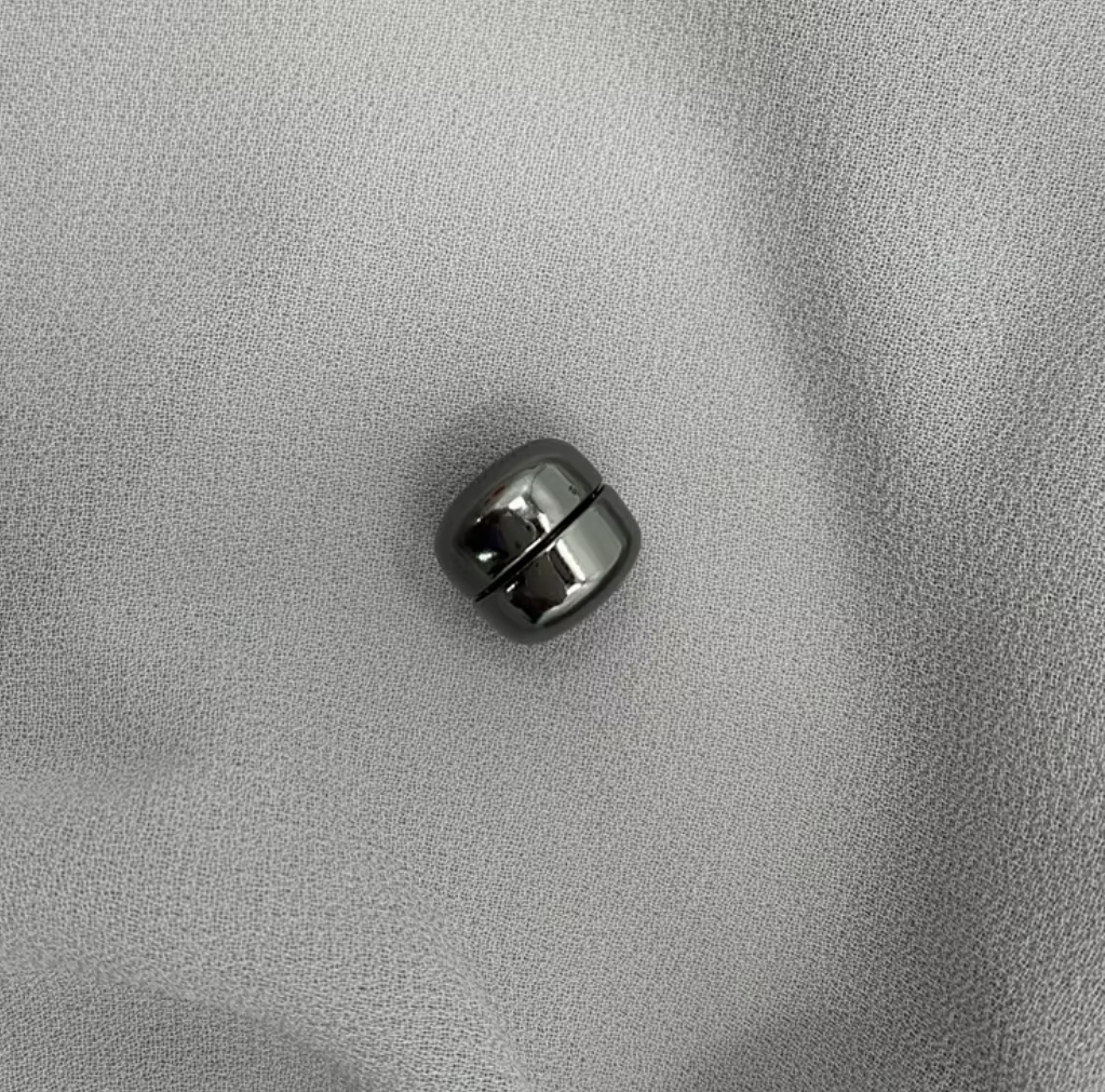 Black magnetic ball on a gray textured surface