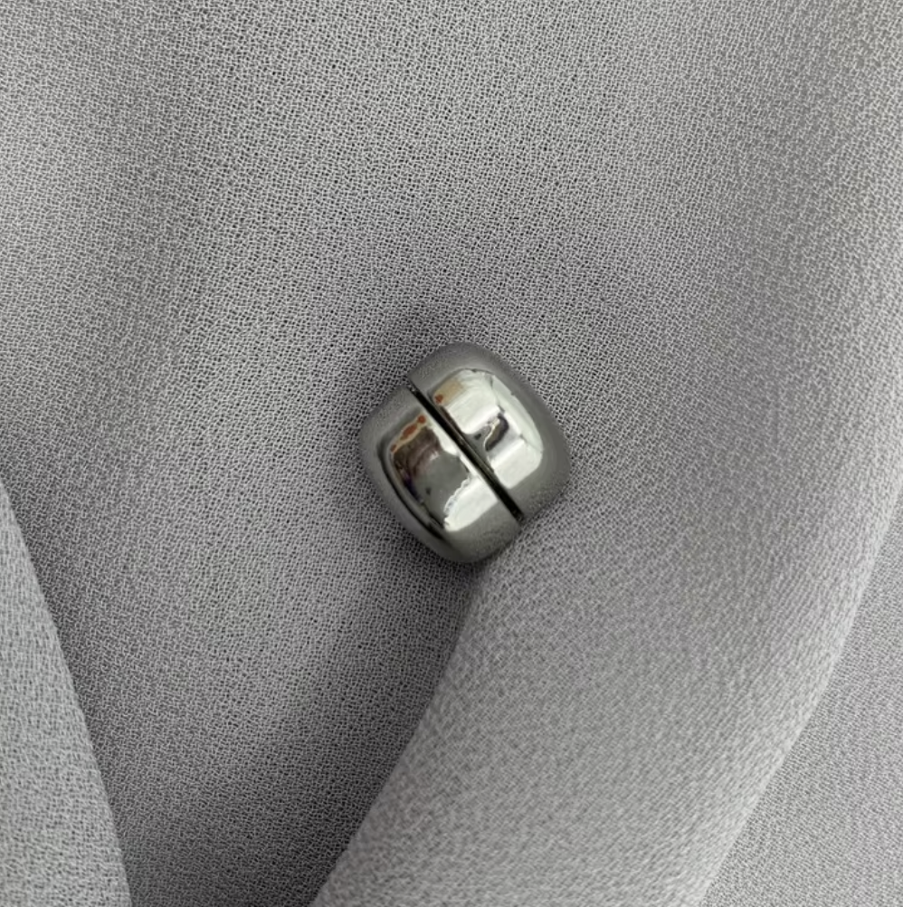 Metallic button on a textured gray fabric surface