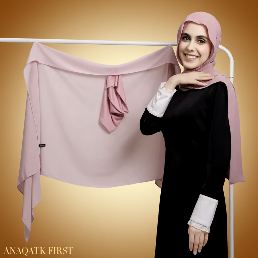 Woman wearing a pink hijab and black outfit with a white background