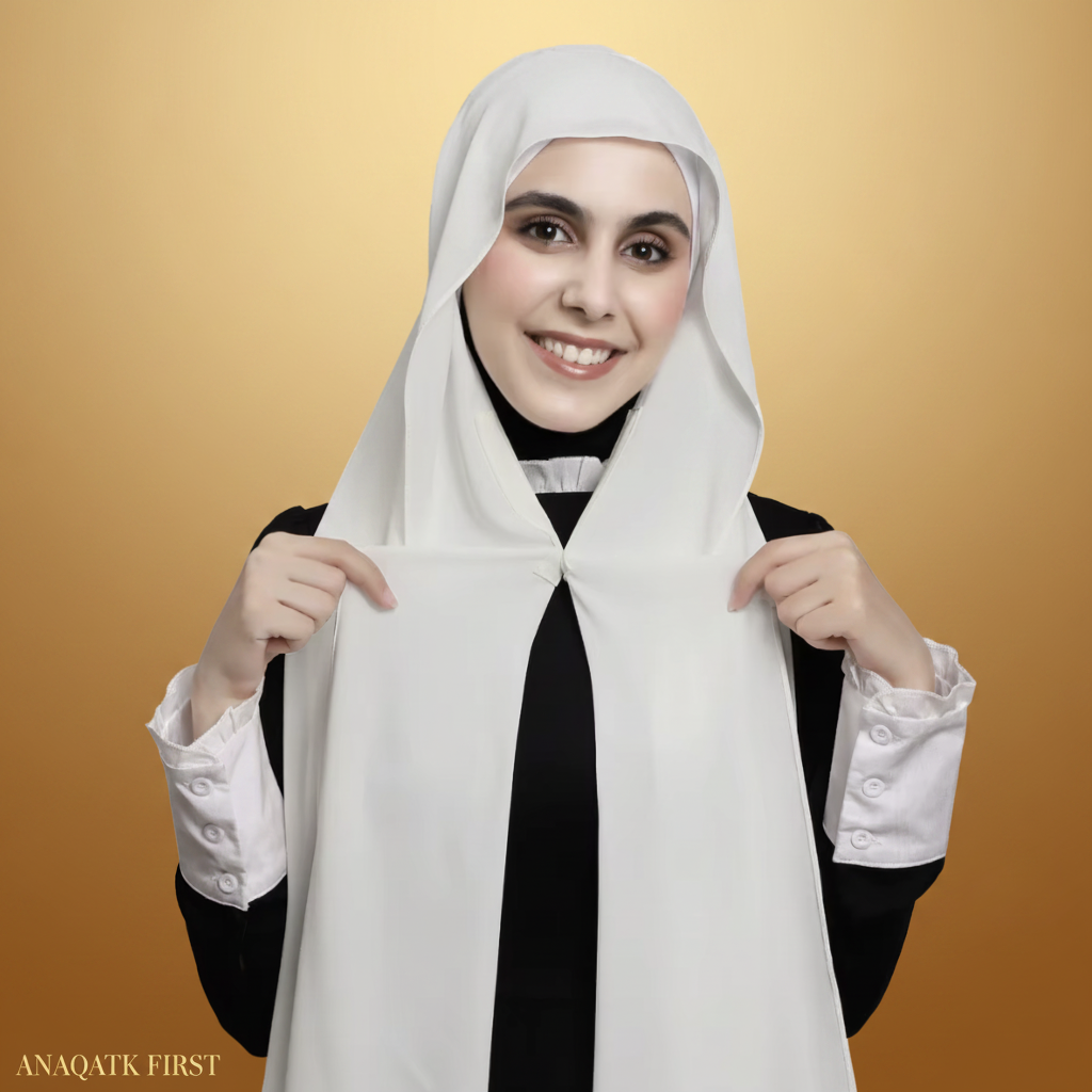 Person wearing a white hijab with a black and white outfit on a light gray background