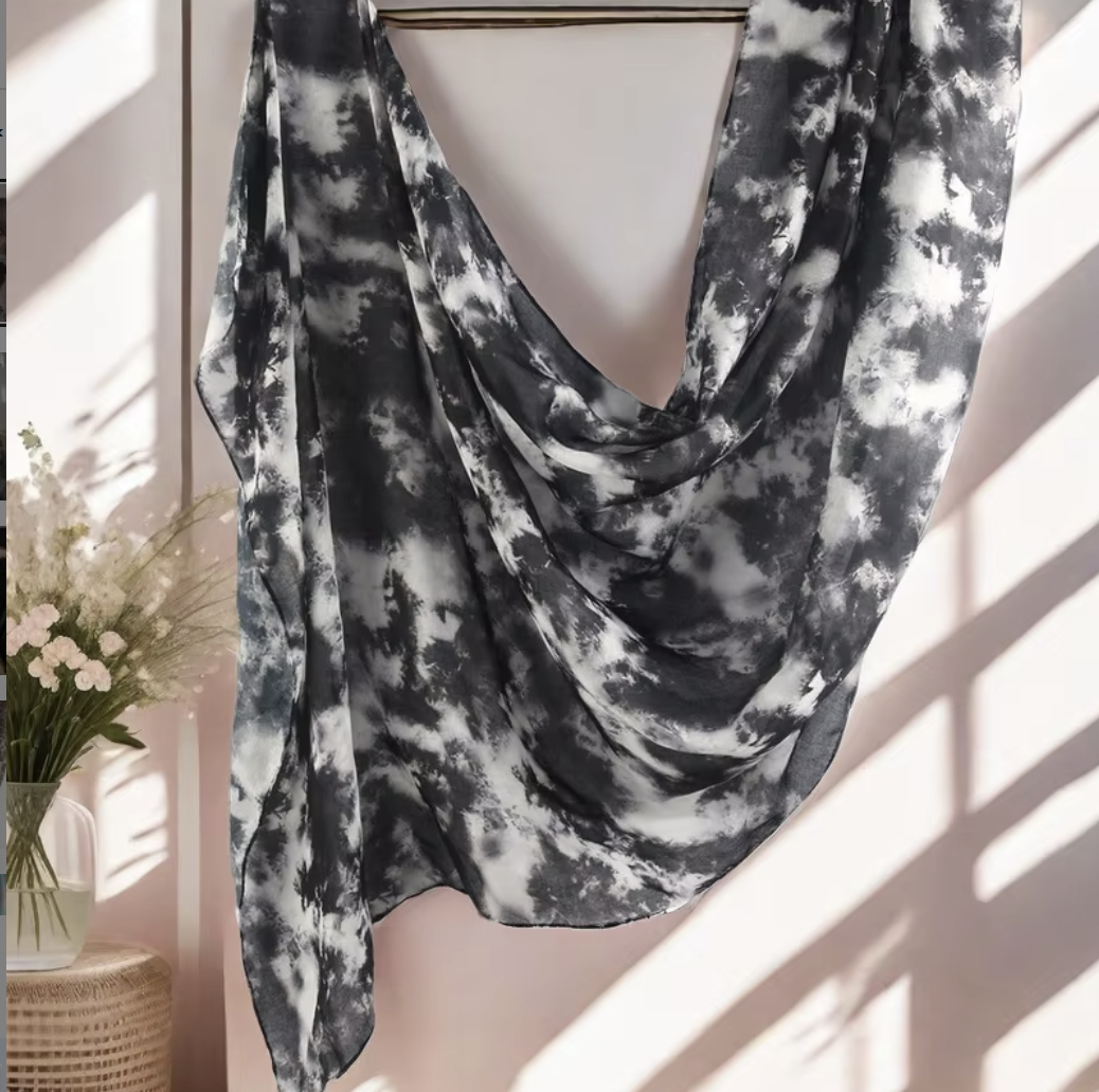 Black and white tie-dye scarf draped over a mannequin against a neutral background.