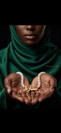 Person wearing a green hijab holding two gold bracelets with Arabic text on a dark background
