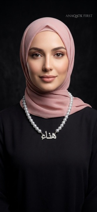 Woman wearing a pink hijab and black top with visible branding on a dark background